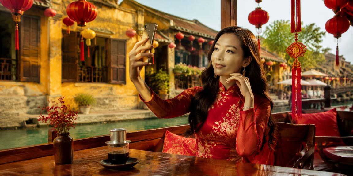 Khách du lịch tại Hội An vừa uống cà phê vừa trải nghiệm trò chơi baccarat trực tuyến trên điện thoại